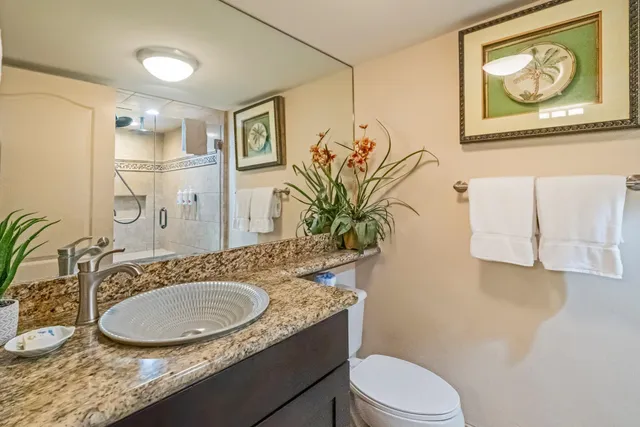 a bathroom with a granite countertop sink mirror vanity and toilet