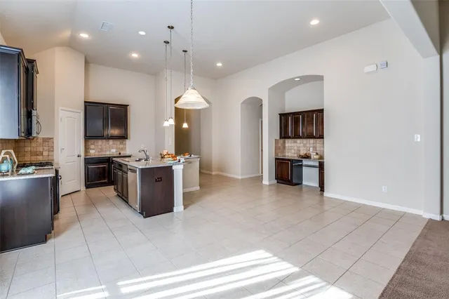 a large white kitchen with a sink a counter top space appliances and cabinets