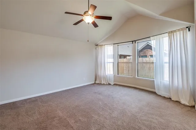 an empty room with chandelier fan and windows