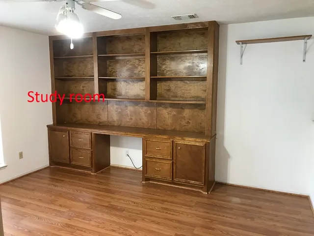 an empty room with wooden floor and cabinet