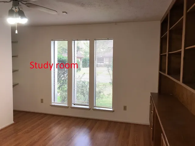 a view of an empty room with wooden floor and windows