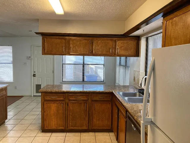a kitchen with granite countertop a sink and a refrigerator
