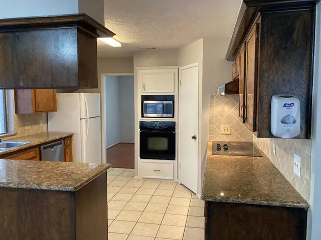 a kitchen with granite countertop a sink and a refrigerator