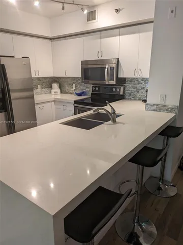 a kitchen with a sink a stove a microwave a refrigerator a stove and island