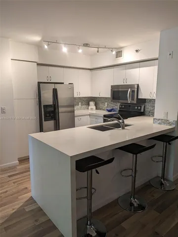 a kitchen with a kitchen island wooden cabinets and refrigerator