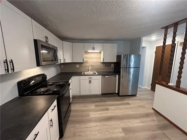 a kitchen with granite countertop a refrigerator stove and sink
