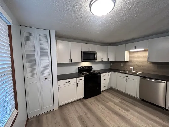 a kitchen with granite countertop a stove top oven sink and cabinets