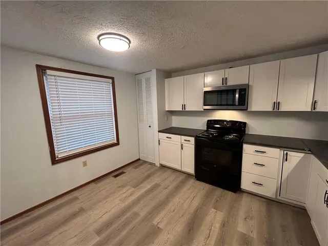 a kitchen with granite countertop white cabinets and black appliances