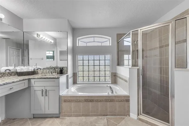 a bathroom with a granite countertop bathtub shower sink vanity and mirror