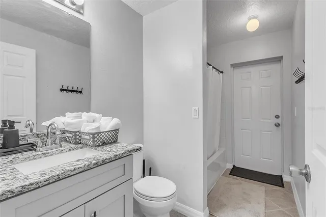 a bathroom with a granite countertop sink mirror vanity and toilet