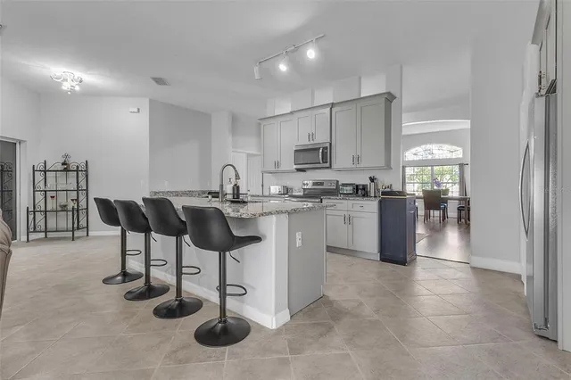 a kitchen with stainless steel appliances granite countertop a table chairs and a refrigerator