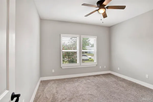an empty room with a window and a fan