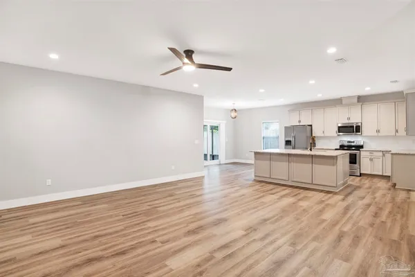 a large kitchen with cabinets wooden floor and a sink