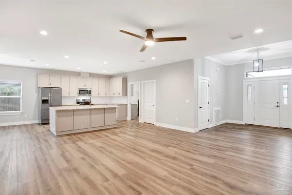 a view of a kitchen with kitchen island a sink wooden floor and a refrigerator