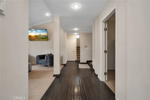 a view of a hallway with wooden floor and a bathroom