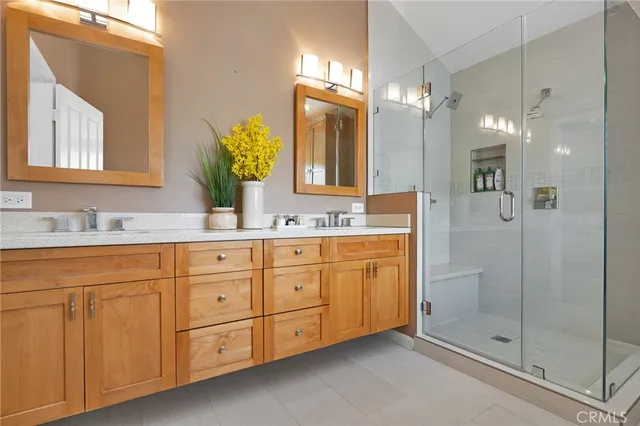 a bathroom with a granite countertop double vanity sink mirror and shower