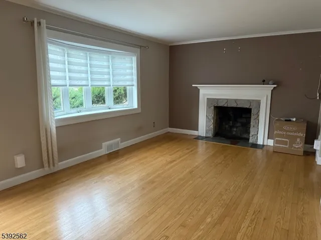 an empty room with wooden floor fireplace and windows