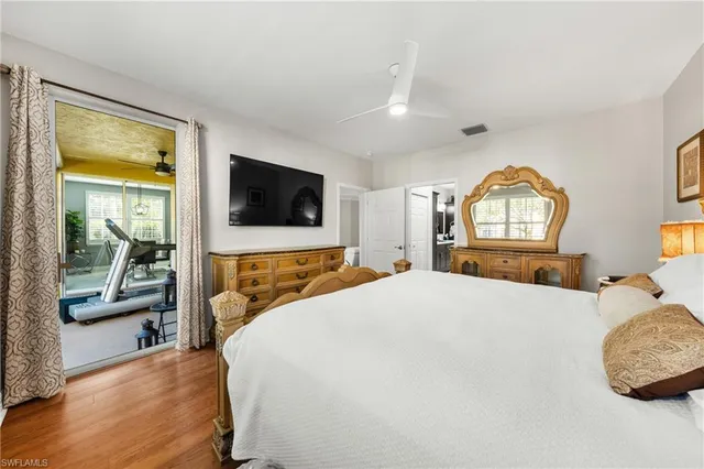 a bedroom with a bed a mirror and a flat tv screen on dresser