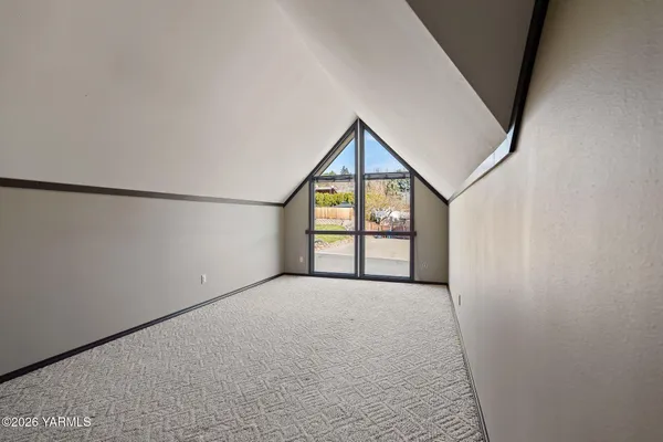 a view of an empty room with a window and fireplace