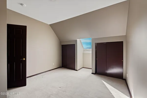 a view of an empty room with closet and a bathroom