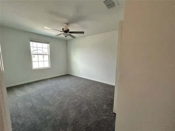 an empty room with windows and ceiling fan