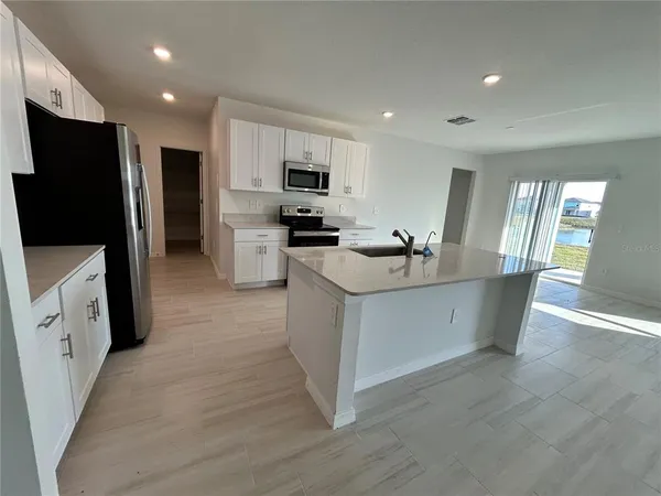 a kitchen with stainless steel appliances kitchen island granite countertop a stove a sink a refrigerator a microwave a sink and a refrigerator