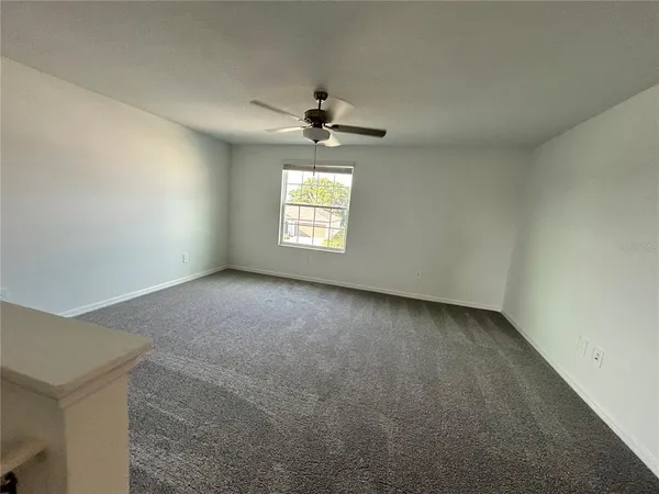 an empty room with a window and a fan