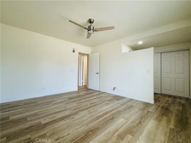 a view of empty room with wooden floor and fan