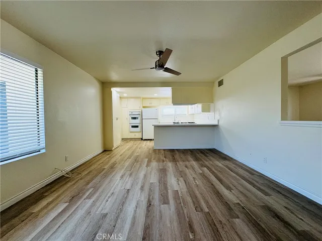 a view of kitchen and empty room with wooden floor