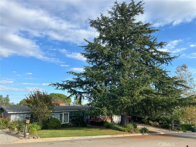 a view of a house with a yard and large trees