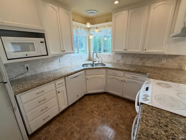 a kitchen with granite countertop a sink a stove and cabinets