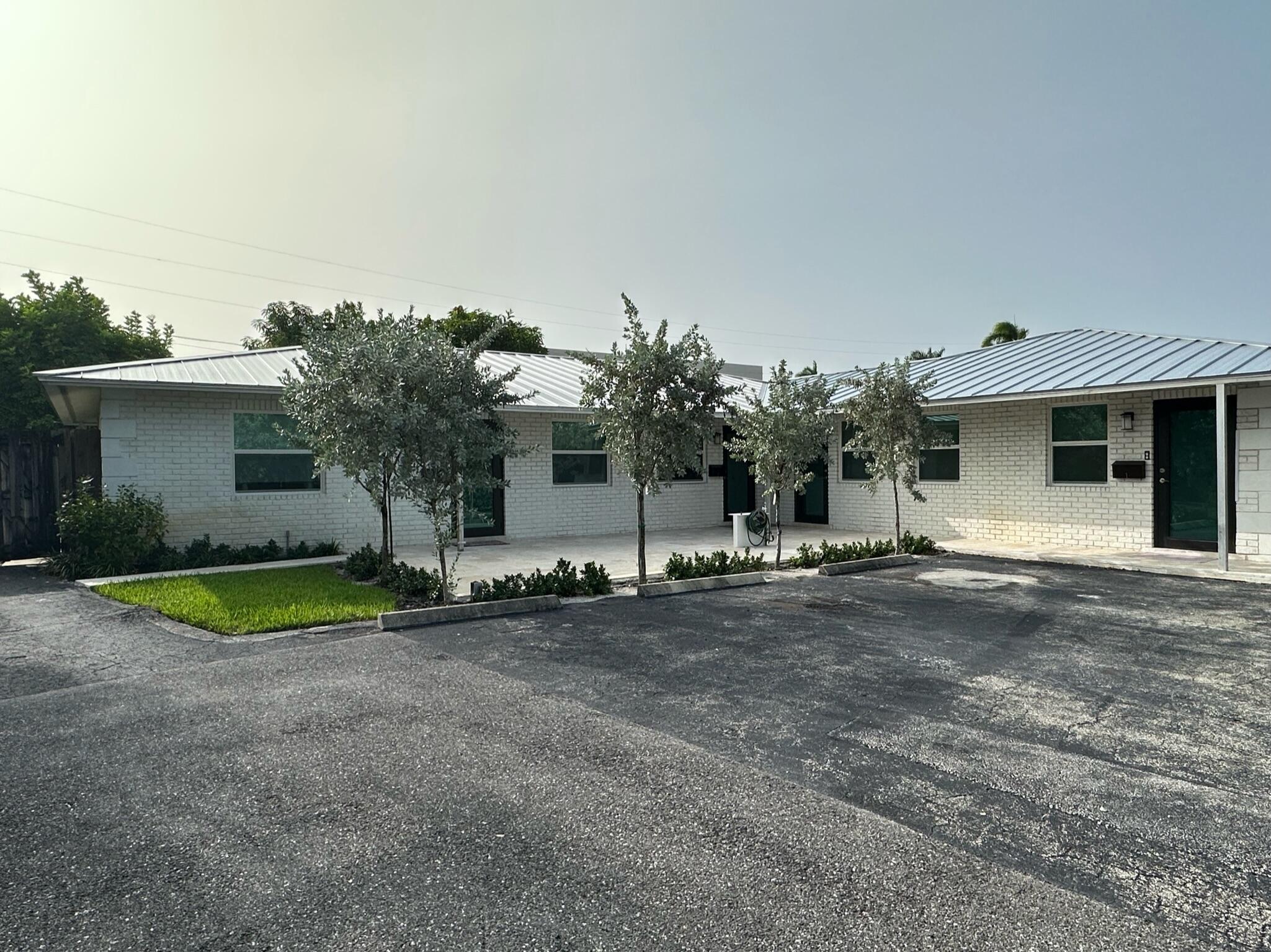 2018 Spanish Trail, Unit 2 Delray Beach, FL 33483 - Photo 2 of 13 a front view of a house with a yard and garage