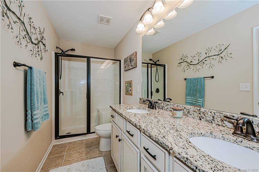 287 Annatto Way Tega Cay, SC 29708 - Photo 22 of 32 a bathroom with a granite countertop sink a large mirror and a shower