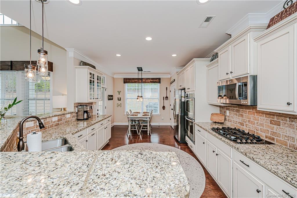 287 Annatto Way Tega Cay, SC 29708 - Photo 8 of 32 a kitchen with stainless steel appliances granite countertop a sink stove refrigerator and cabinets