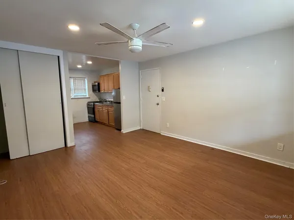 an empty room with wooden floor and a kitchen