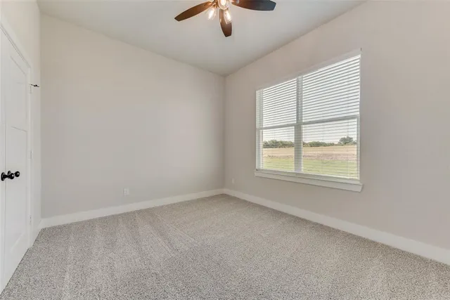 an empty room with a window and a ceiling fan