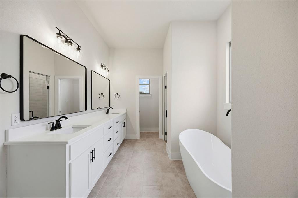 6713 Odom Road Sanger, TX 76266 - Photo 24 of 32 a spacious bathroom with a double vanity sink a mirror and a bathtub