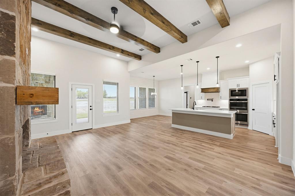 6713 Odom Road Sanger, TX 76266 - Photo 4 of 32 a kitchen with stainless steel appliances kitchen island wooden floors and white walls