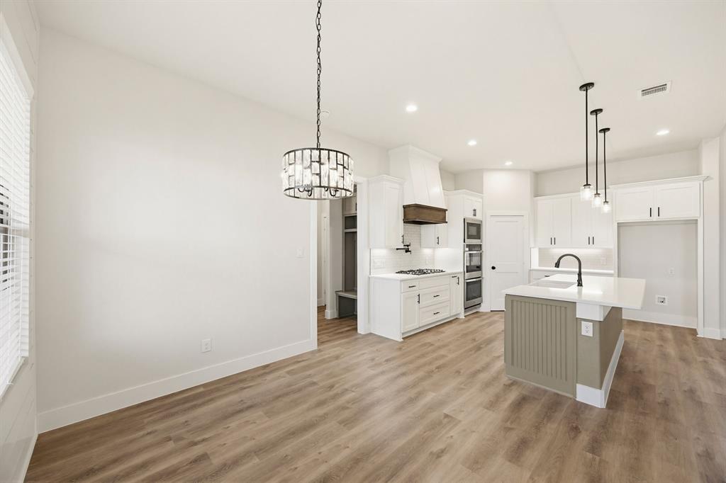 6713 Odom Road Sanger, TX 76266 - Photo 8 of 32 a open kitchen with a refrigerator a sink dishwasher a oven and a dining table with wooden floor