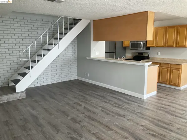 a view of kitchen with stainless steel appliances wooden floor and window
