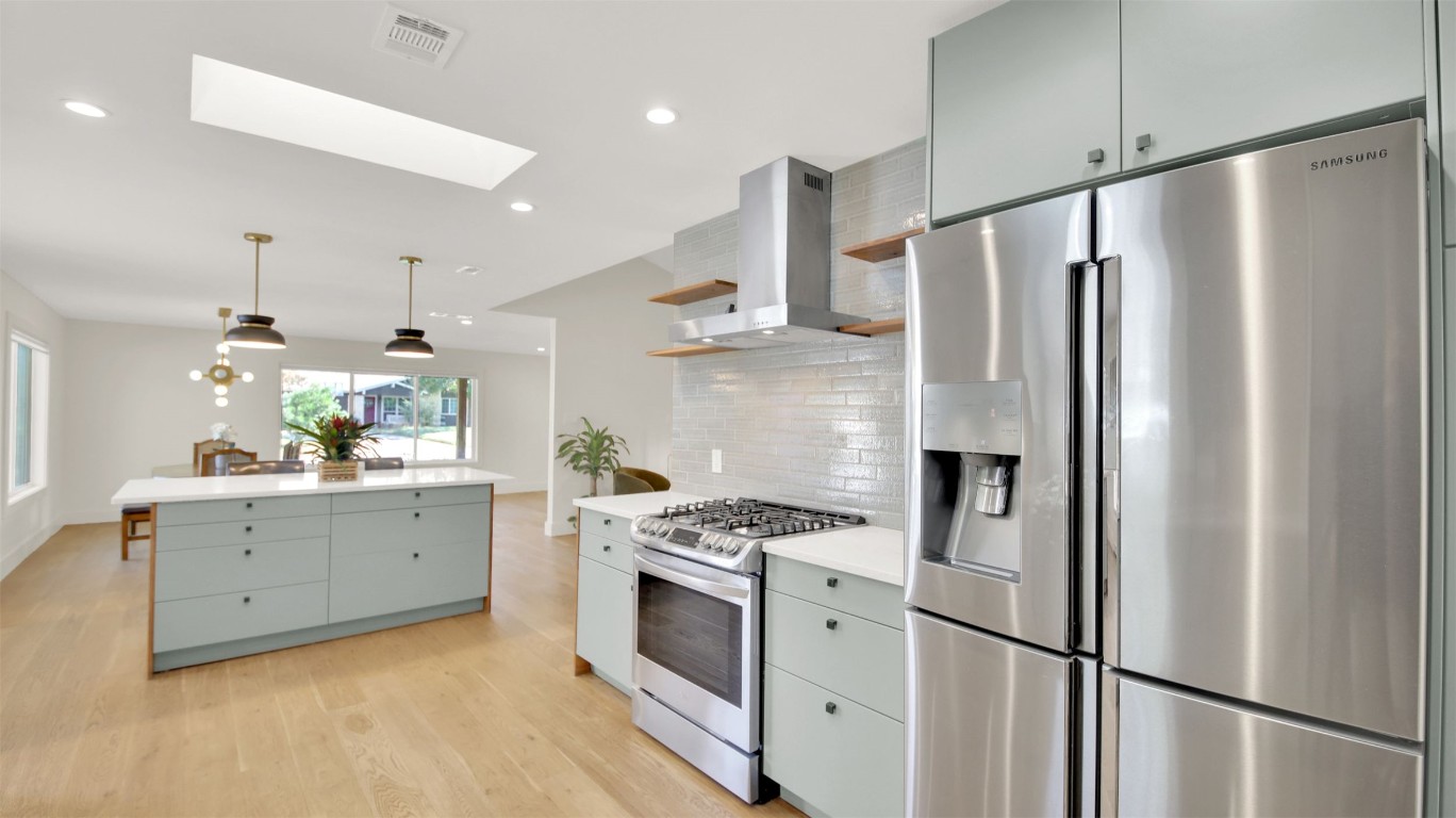 7510 Daugherty Street Austin, TX 78757 - Photo 18 of 37 Kitchen with appliances with stainless steel finishes, open shelves, a skylight, gray cabinets, and recessed lighting