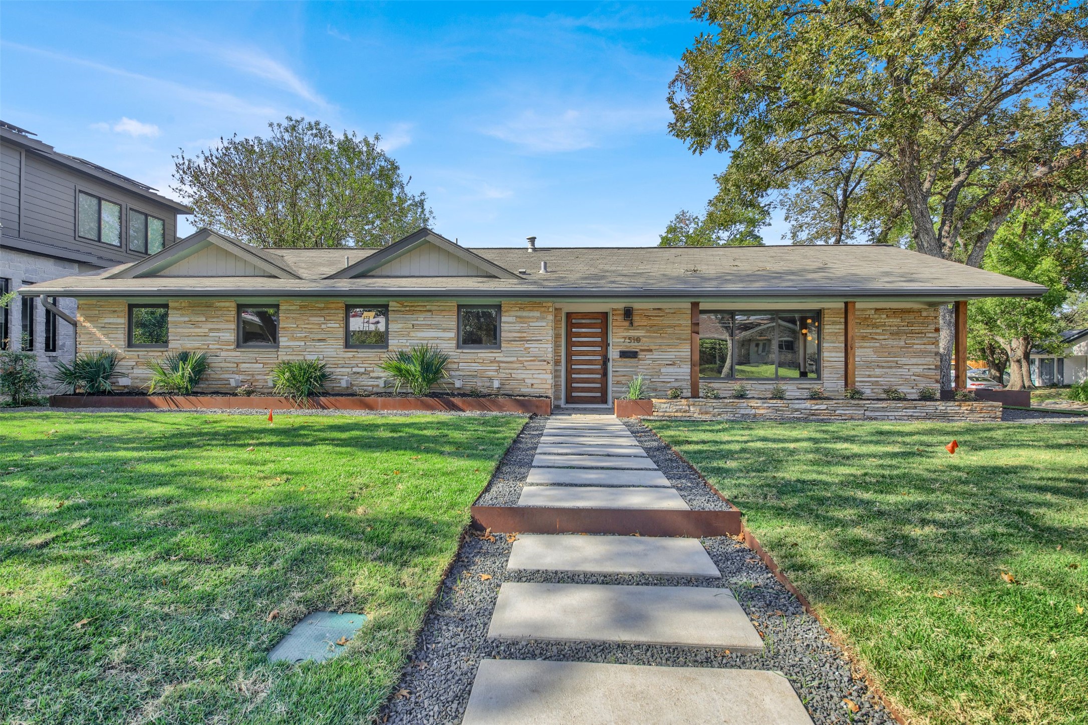 7510 Daugherty Street Austin, TX 78757 - Photo 2 of 37 View of front of property with stone siding, a front lawn, and a shingled roof