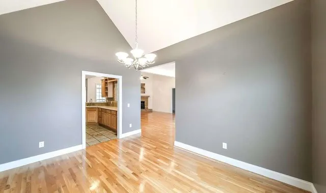 an empty room with wooden floor and fan