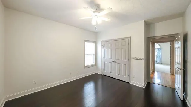 an empty room with windows and ceiling fan