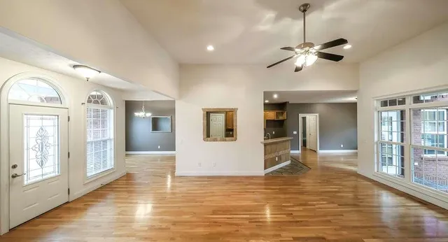 a view of an empty room with wooden floor and a window
