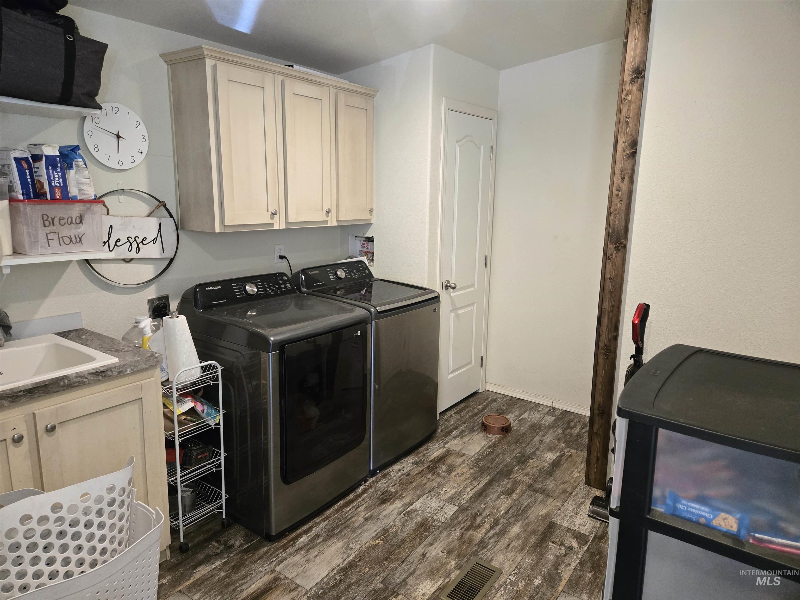 174 Konkolville Road Orofino, ID 83544 - Photo 30 of 43 Laundry area featuring wood-finish flooring, light-colored upper cabinetry, a utility sink with a laminate countertop, and a white paneled door