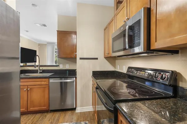 a kitchen with stainless steel appliances granite countertop a stove a sink and a microwave