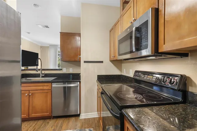 a kitchen with stainless steel appliances granite countertop a stove a sink and a microwave