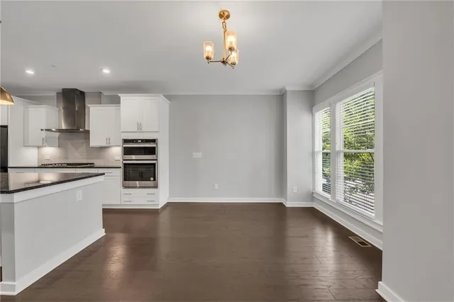 a kitchen with stainless steel appliances granite countertop sink stove and white cabinets with wooden floor