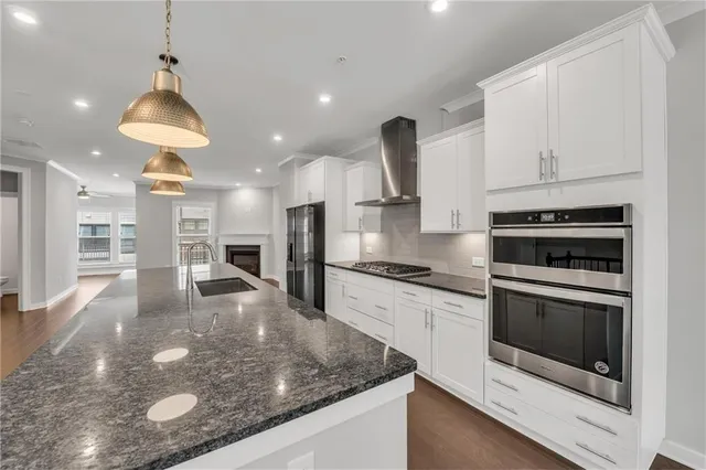 a kitchen with stainless steel appliances granite countertop a sink a stove and a wooden floors